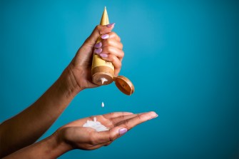 person squeezing tube of sunscreen into their hand