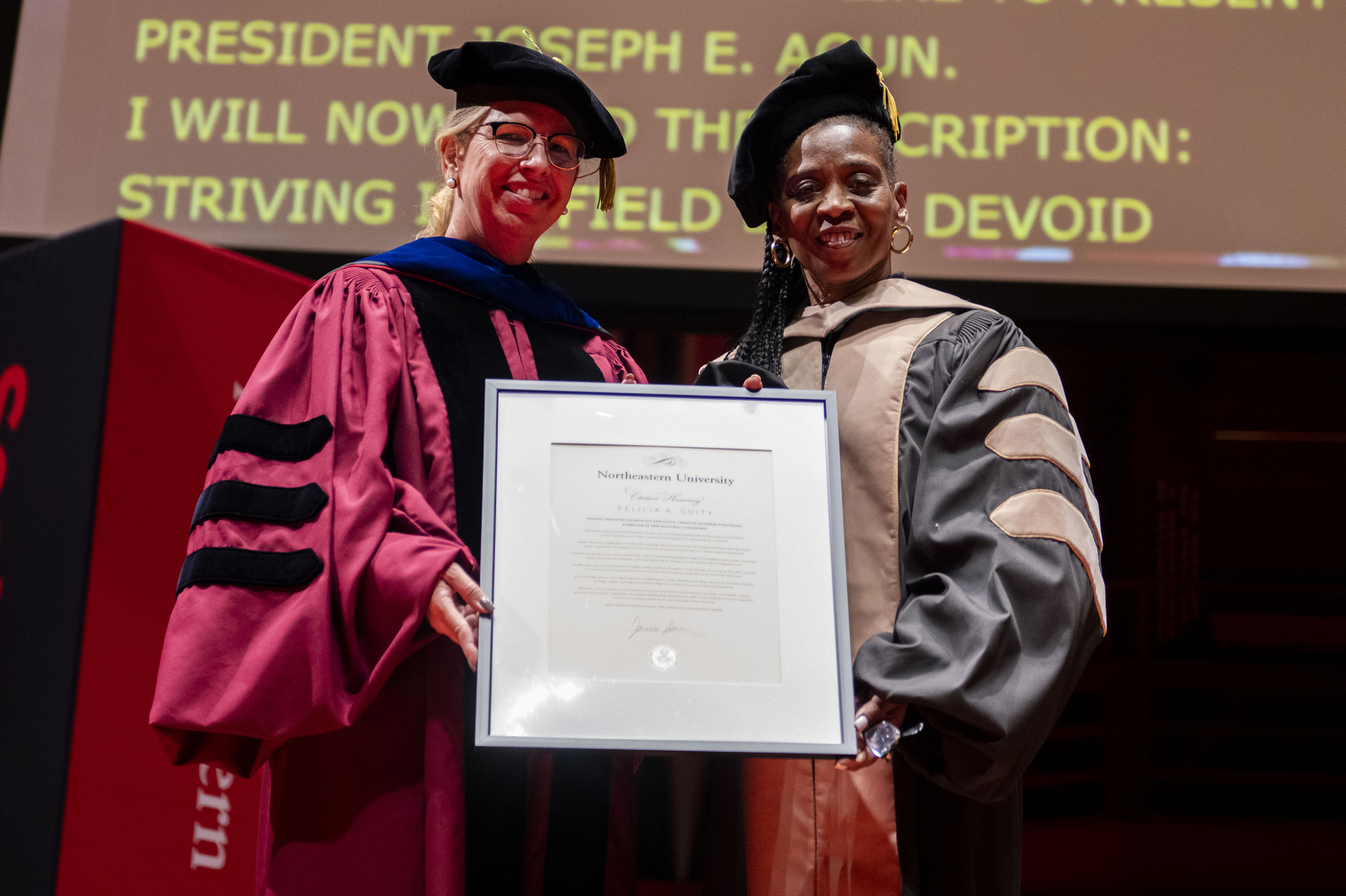 graduate and faculty member posing on stage