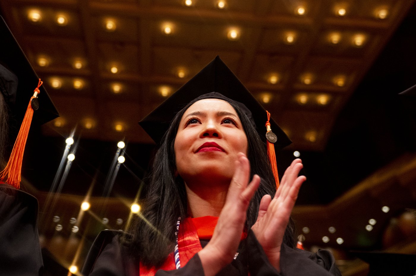 person wearing cap and gown clapping