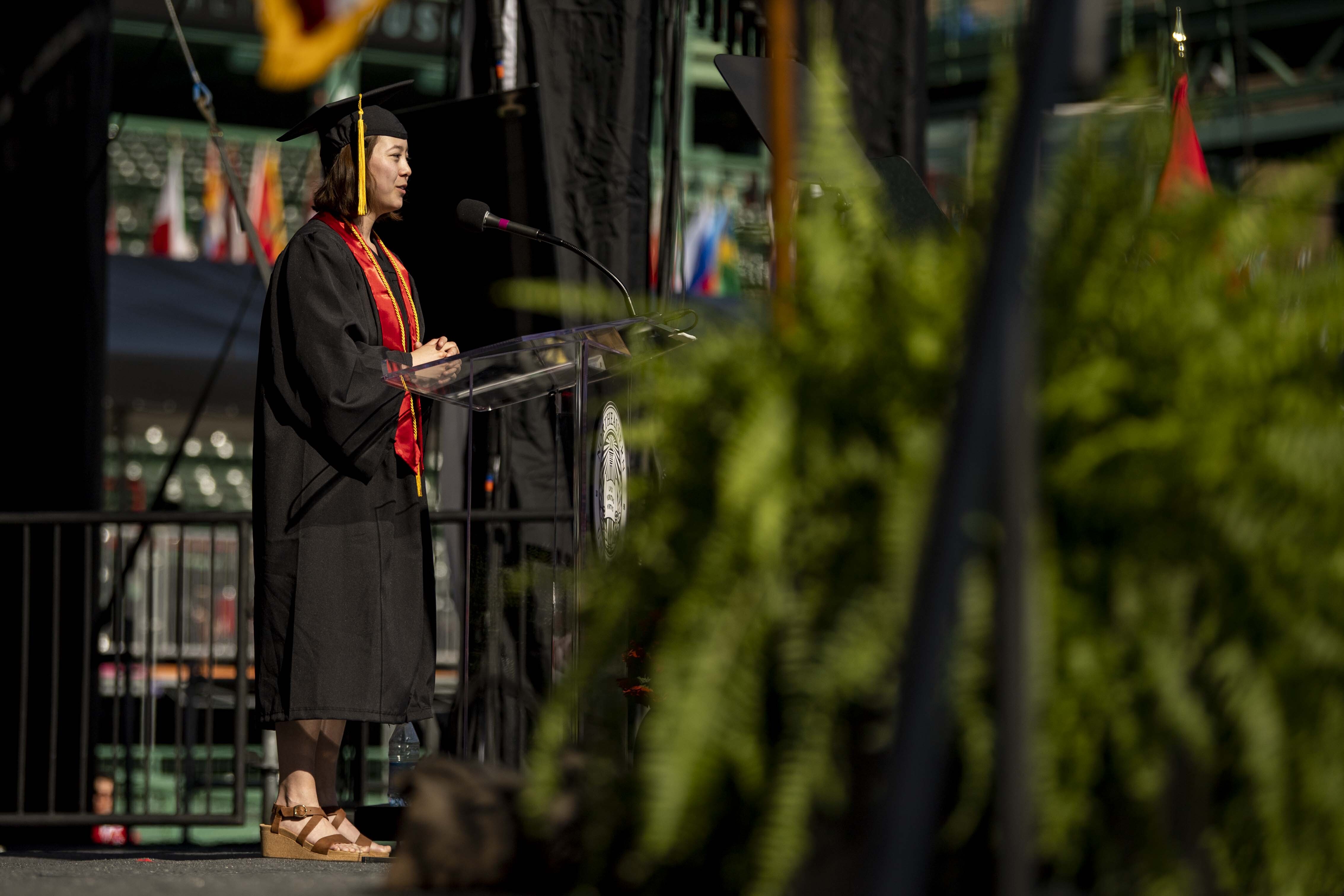 Clara Wu speaking at podium in cap and gown