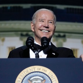 president Joe Biden smiling in front of microphone