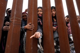 People reach through a metal fence.