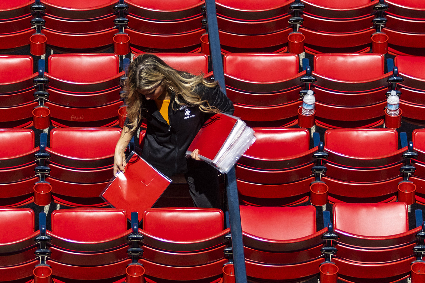 volunteer placing red cards on the seats at Fenway Park