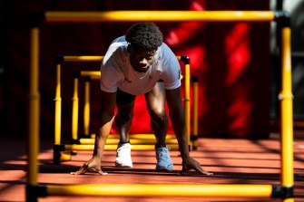 A kneeling runner looks up from the starting line