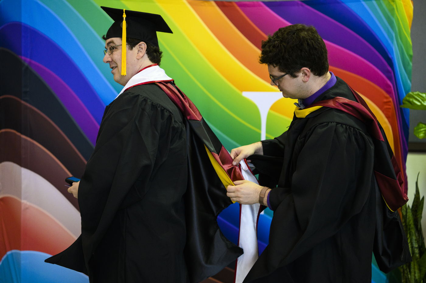 graduates fixing each other's hoods