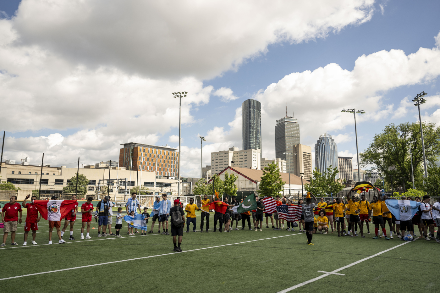 People stand in line on a soccer field holding flags.