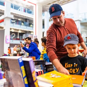 A father and son look at a graphic novel