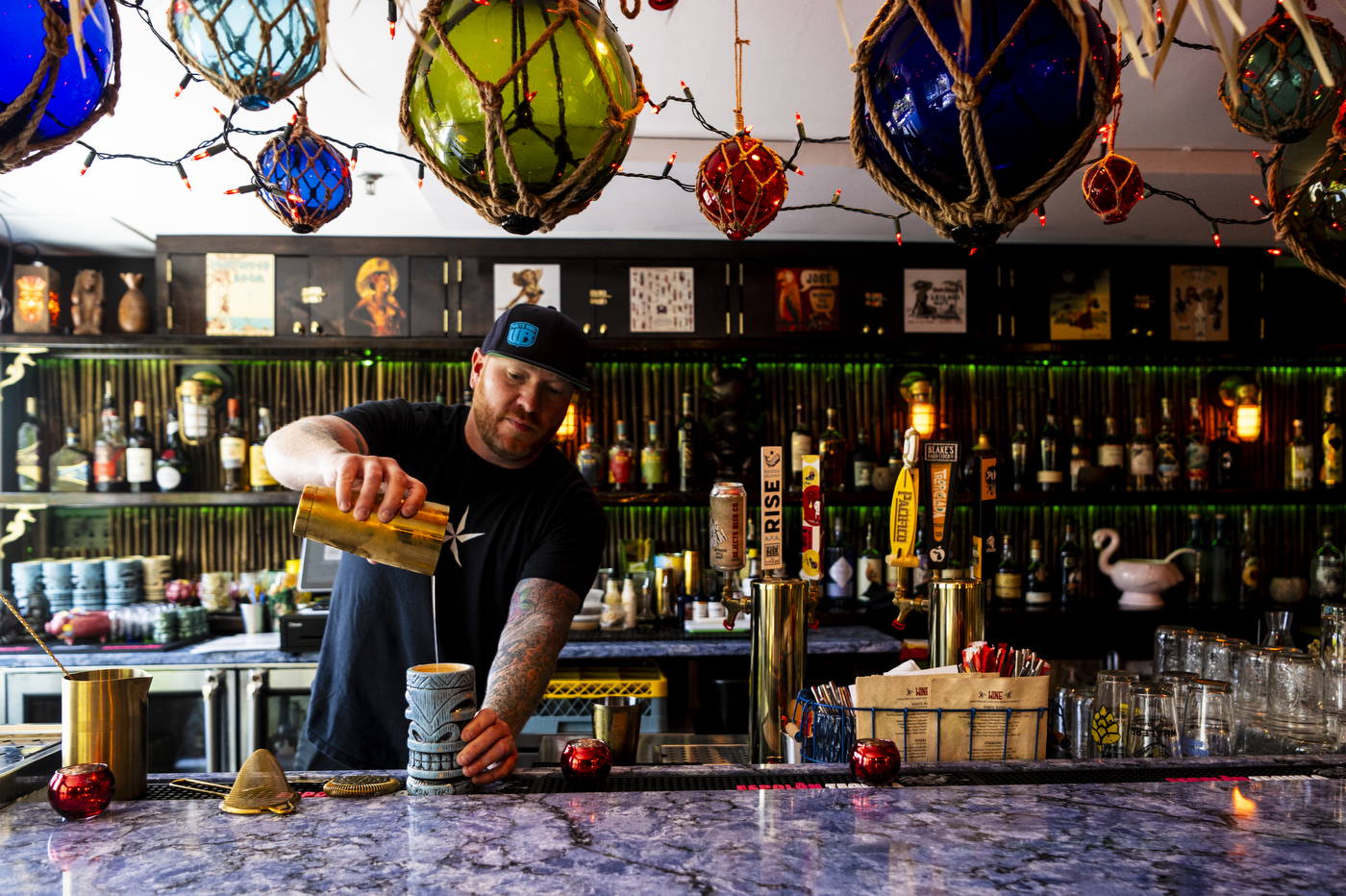 Scott Kirmil pouring a cocktail into a tiki themed glass