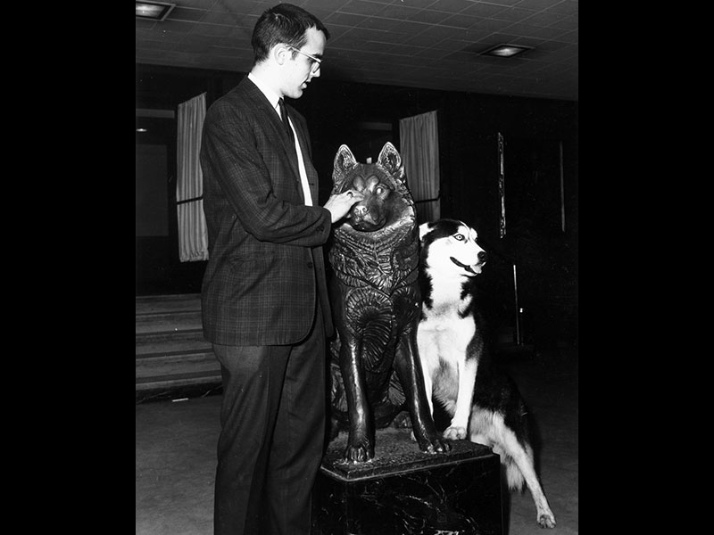 a student rubbing the king husky statue