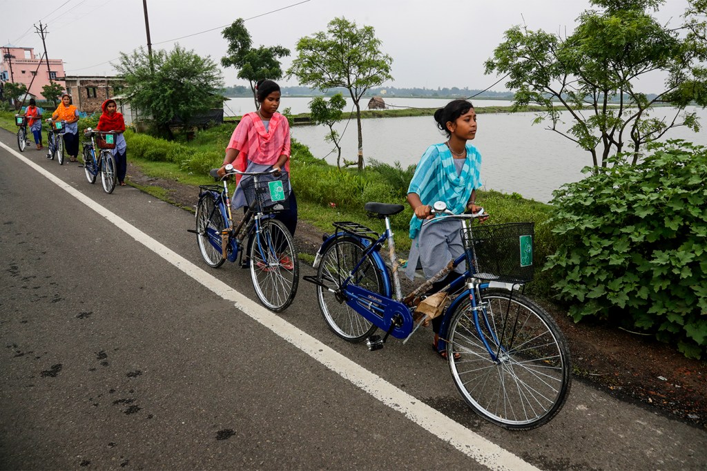 girls walking their bicycles to school