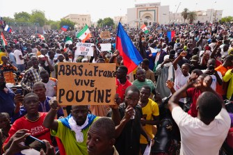 A crowd participates in a large march on a sunny day.