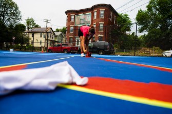 Kaiya Santos working on basketball court painting