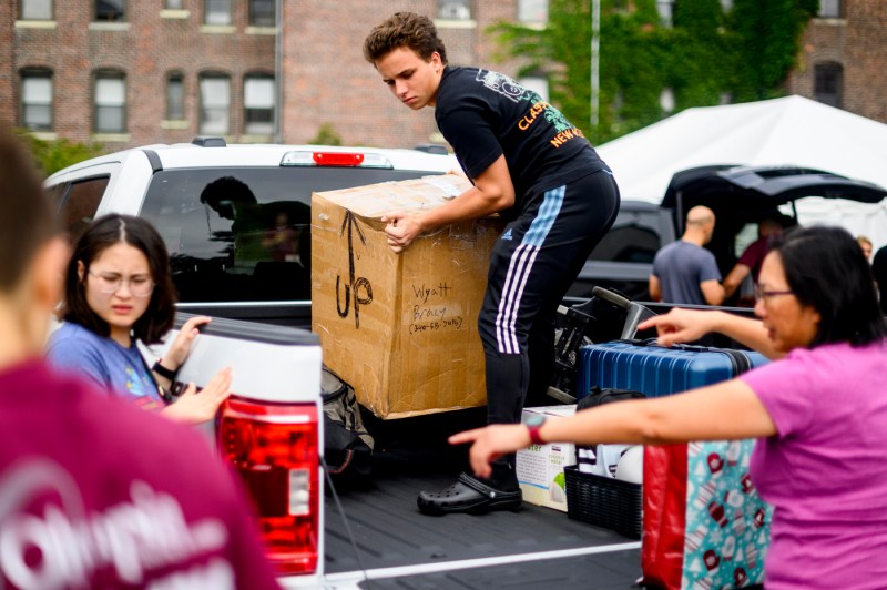 students and family members unloading belongings off the bed of a pickup truck