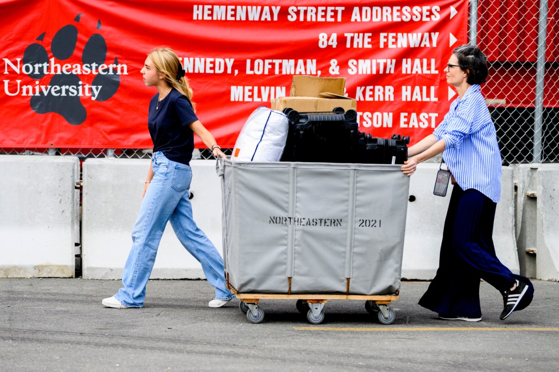 two people wheeling a cart full of suitcases and boxes