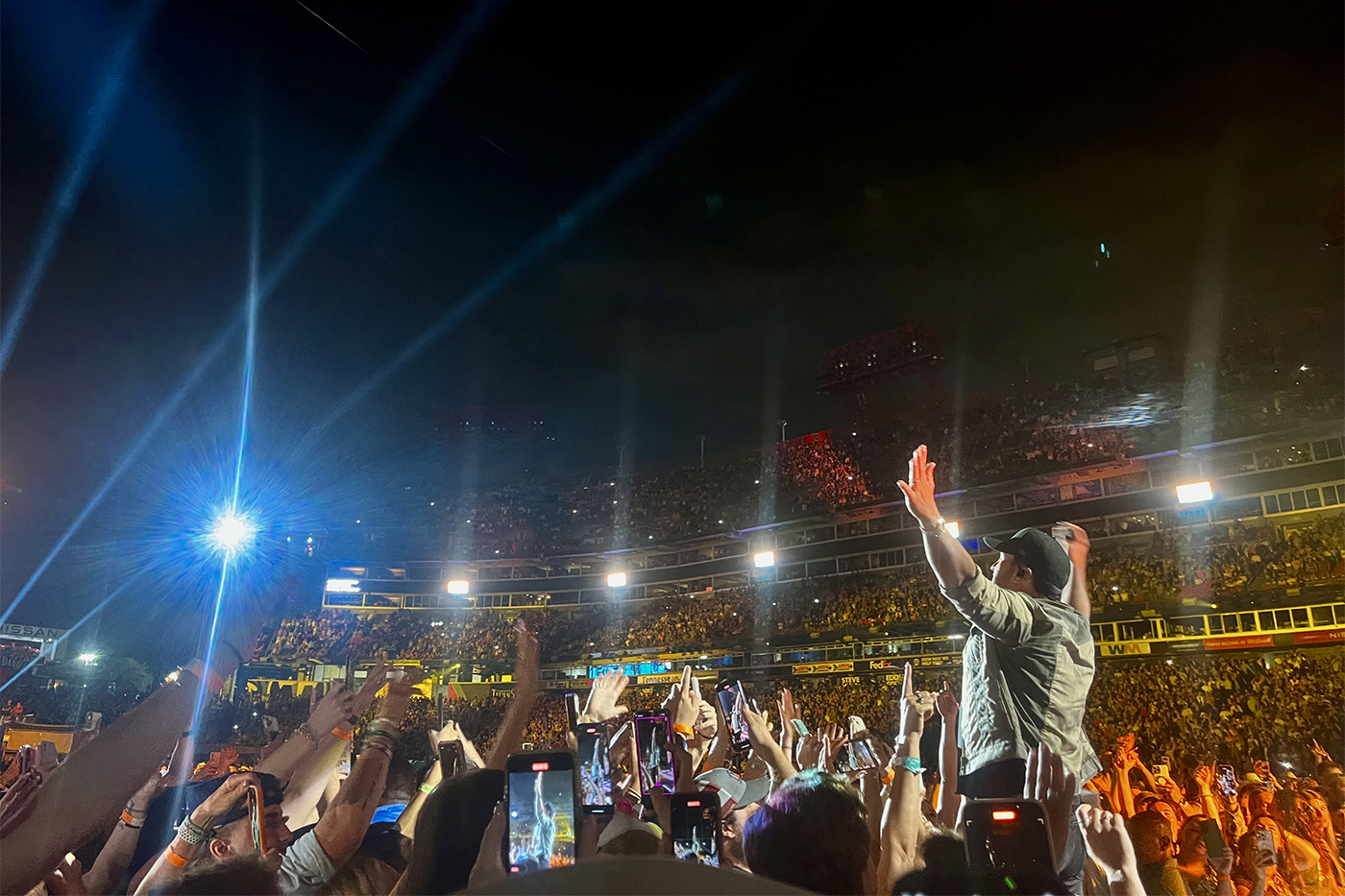 audience members at CMA fest with their hands in the air