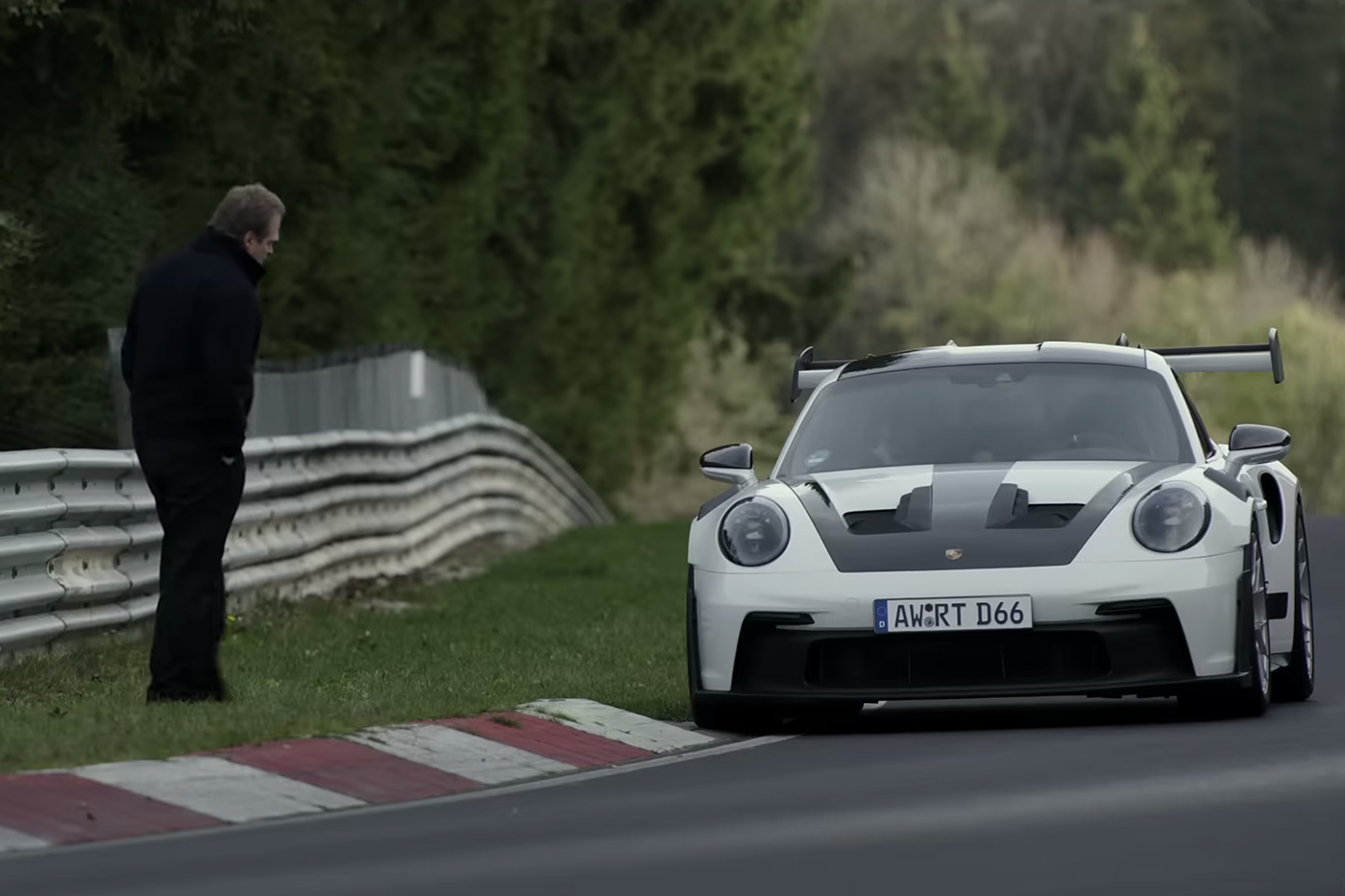 A racecar stopped by the side of the road, an onlooker nearby