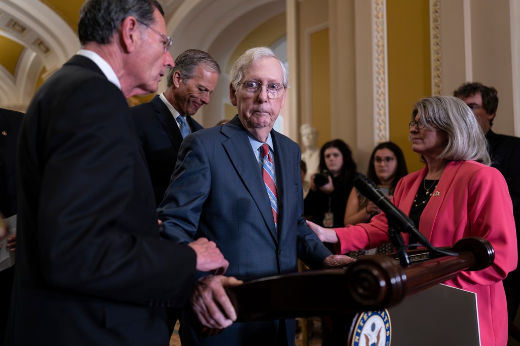 Mitch McConnell being helped by various senators when he froze at a news conference