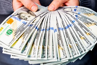 A woman holds a lot of hundred dollar bills in her hands. Without a face. Close-up from a low angle.