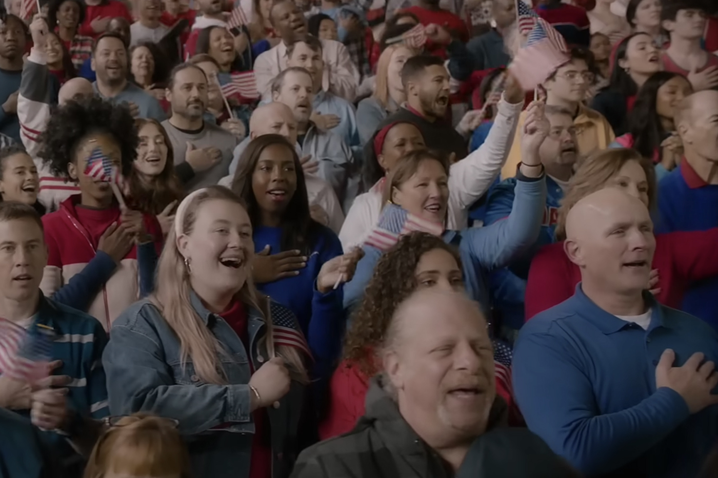 A crowd of people, many waving small United States flags