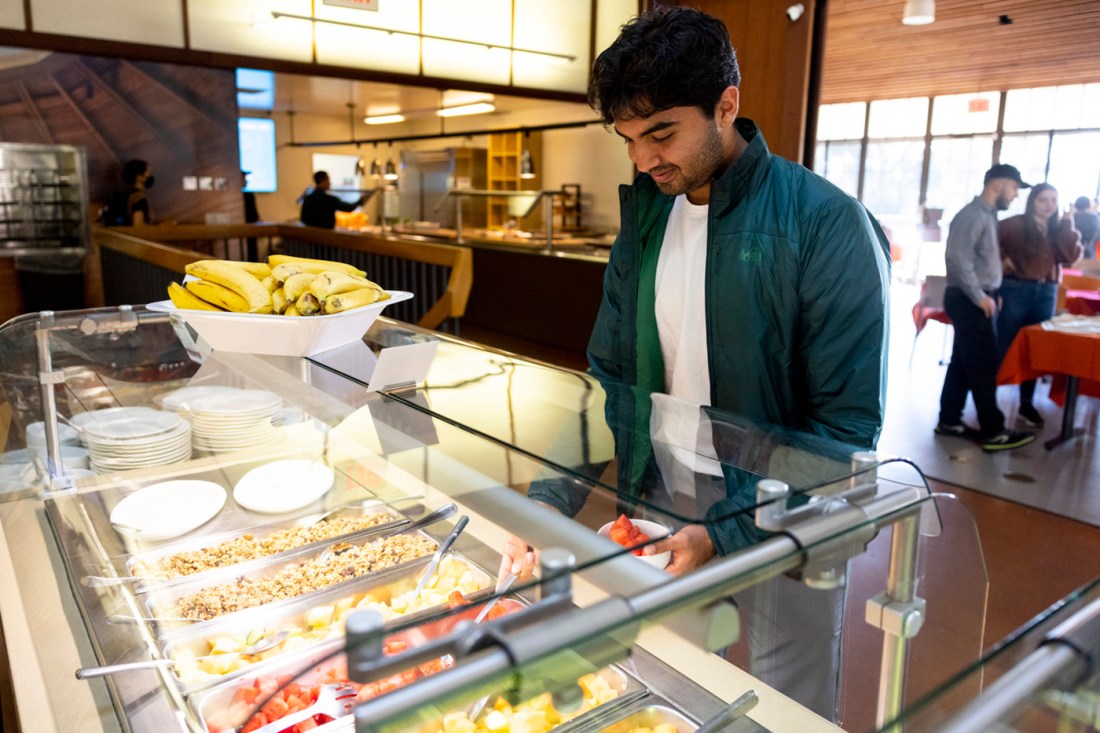 Someone scoops fruit out of a breakfast bar at the food court.