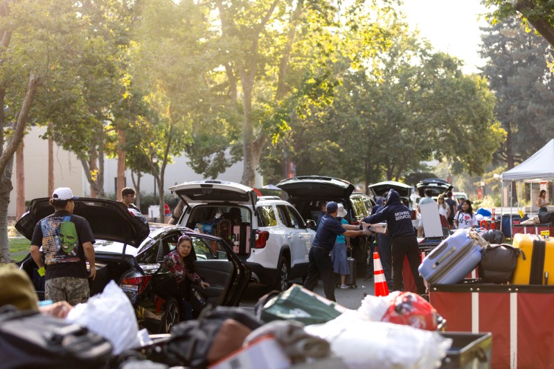 row of cars with their trunks open and people unloading