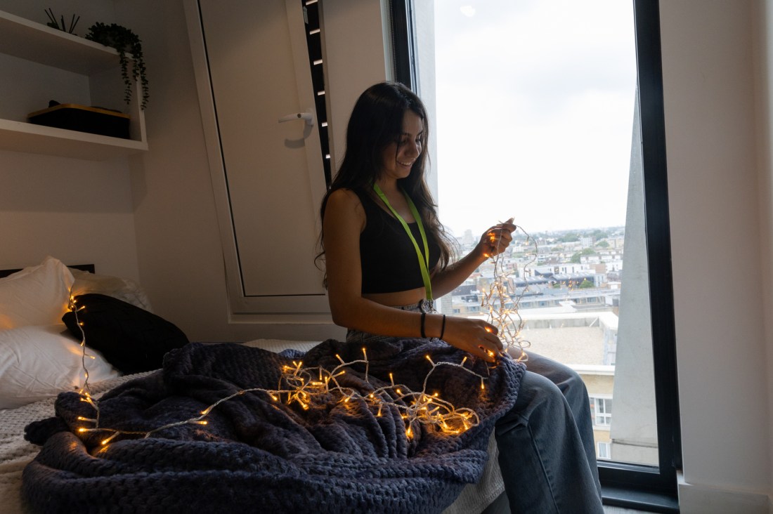 Northeastern community member untangling string lights in their lap. 