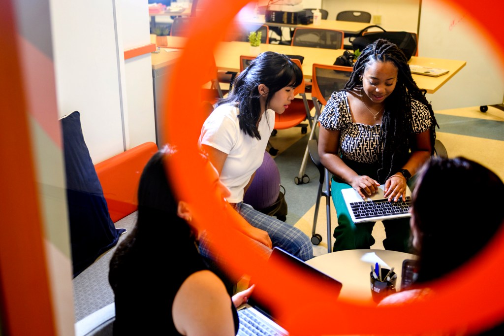 Students work together in groups around a small table.