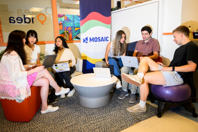 Students work together in groups around a small table.