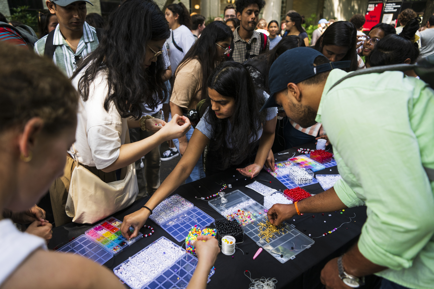 Dozens of people gather around an arts and crafts table.