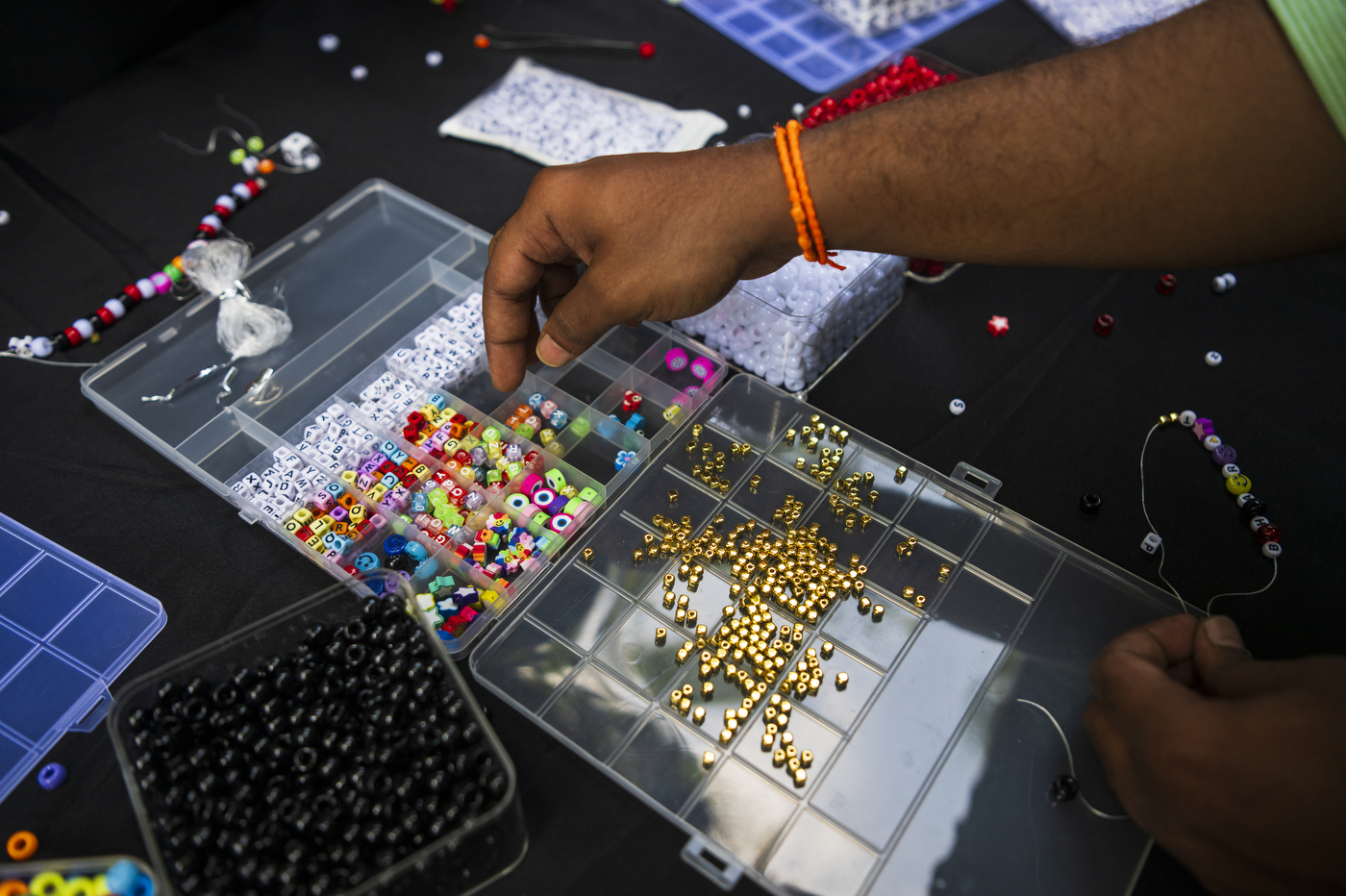 A hand reaches for a bead inside a clear container.