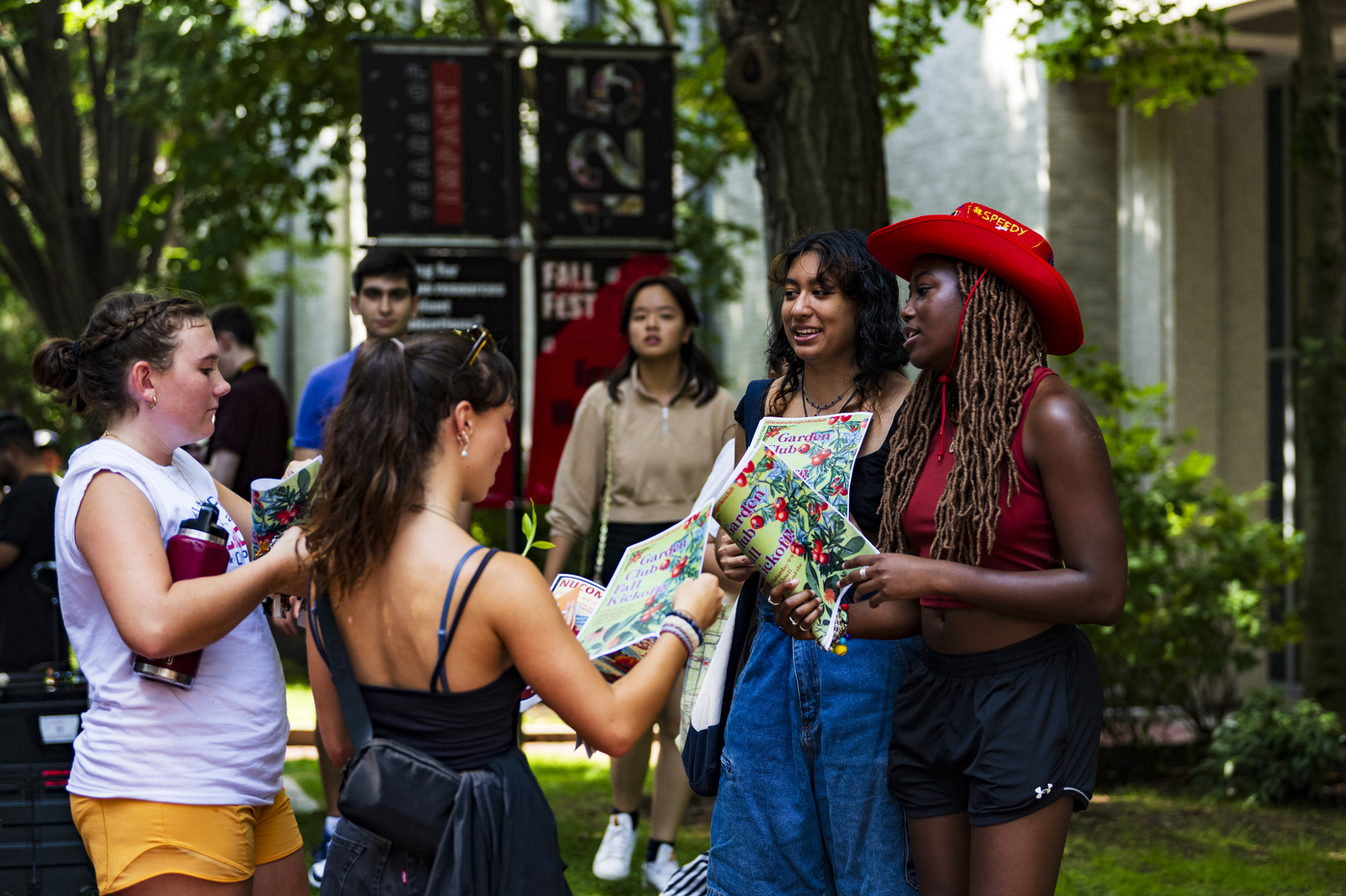 People stand in a circle outside while holding pamphlets.