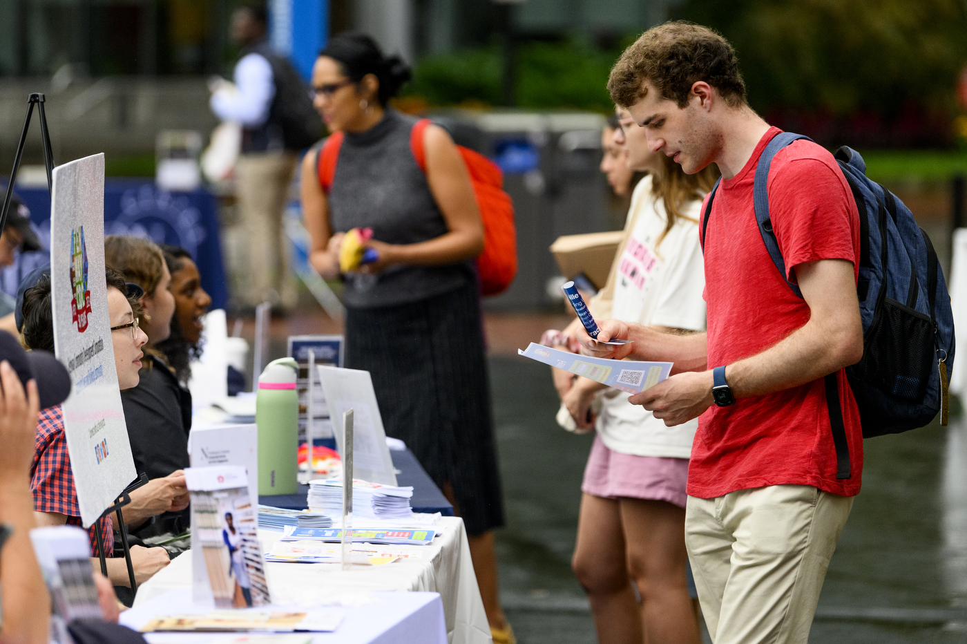 Student wearing red shirt looking down at a piece of paper. 