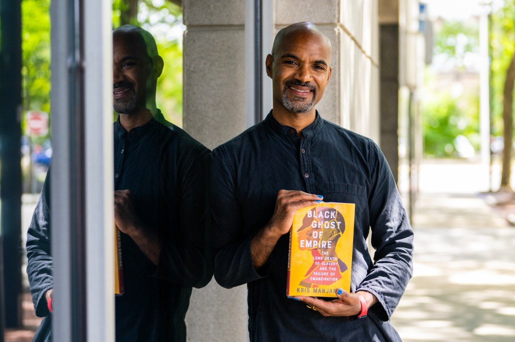 Kris Manjapra holding his book