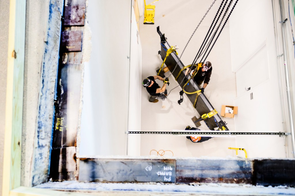 Contractors use a crane to lower a device.