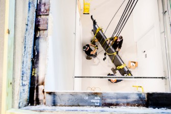 Contractors use a crane to lower a device.