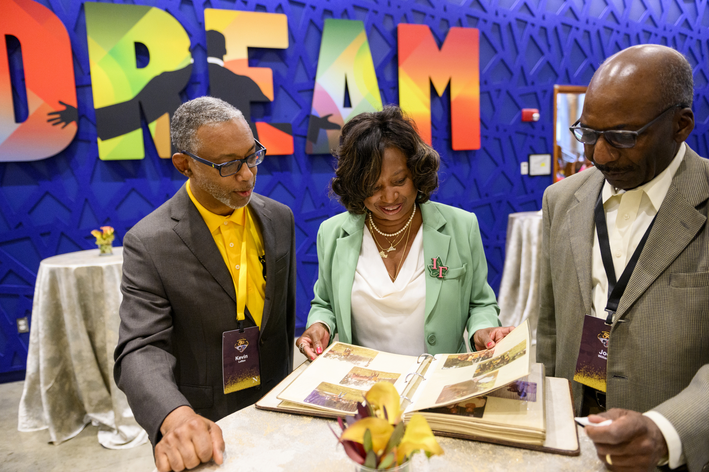 Members of Iota Phi Theta flip through a photo book.