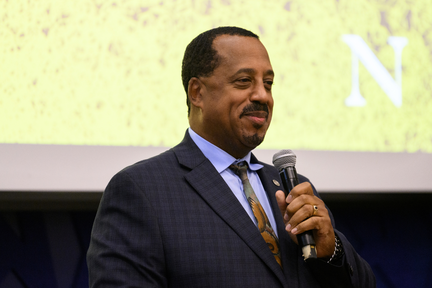 Member of Iota Phi Theta holding a microphone at the 50th Anniversary.