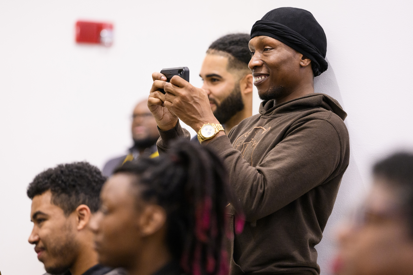 Audience member at Iota Phi Theta's 50th anniversary filming on their phone.