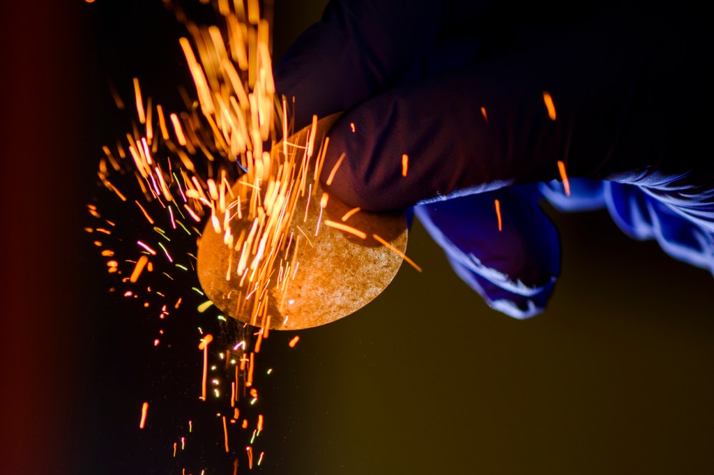 A glove holds a device as sparks fly across the room.