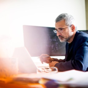 Alessandro Vespignani sitting at a desk looking at a laptop.