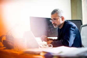 Alessandro Vespignani sitting at a desk looking at a laptop.