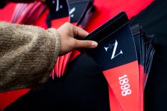 A hand picks up a 1898 red-and-black pennant for Northeastern’s 125th anniversary.