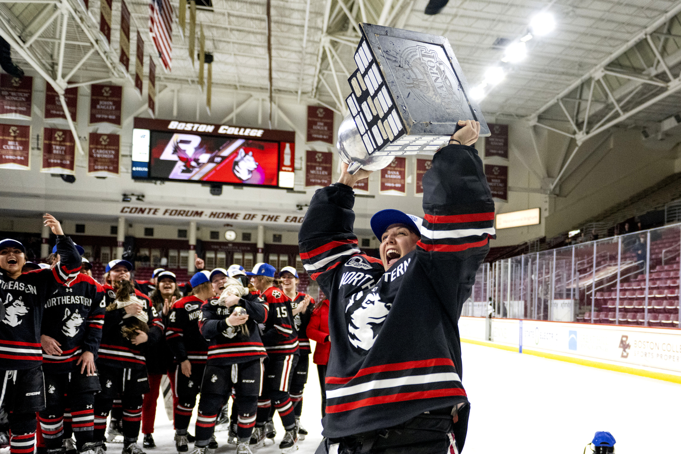 Gwyneth Philips holding hockey trophy above her head.