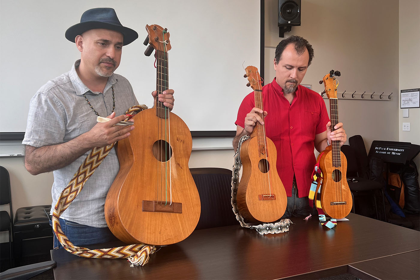 Two people holding three guitars between them.