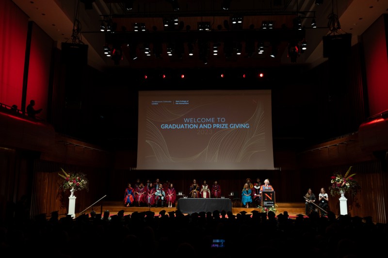 People stand on a stage at Northeastern London's commencement ceremony.