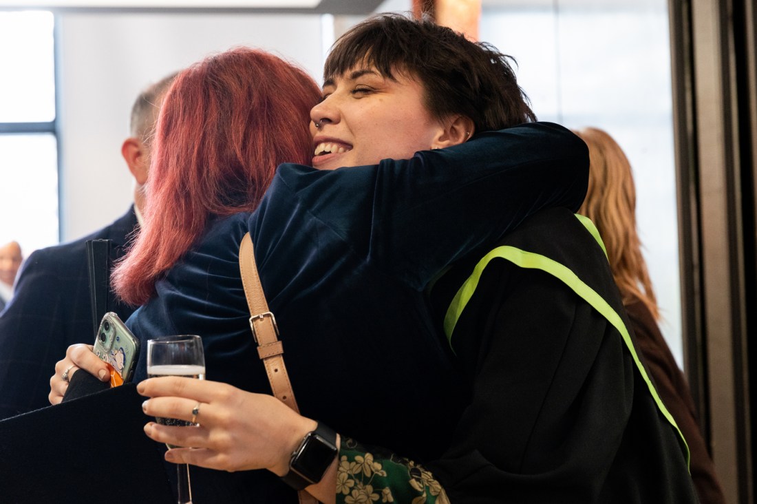 A graduate hugs someone at Graduate speaks Northeastern London's commencement ceremony.