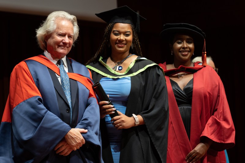 Three people pose for a picture at Northeastern London's commencement ceremony.