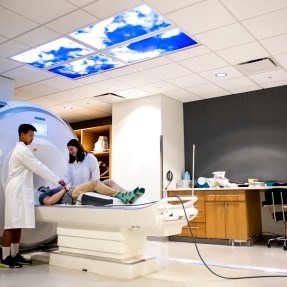 Students putting headphones on a person for an MRI test.