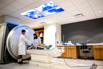 Students putting headphones on a person for an MRI test.