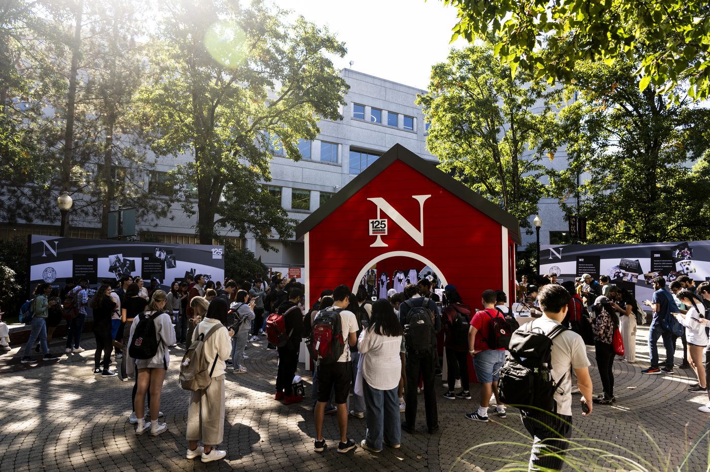 Students walking around a red building with games inside on campus.